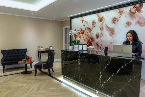 a woman sitting at a reception desk with a laptop at The Boutique Hotel in Rome