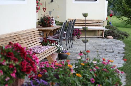 a patio with a table and chairs and flowers at Pension Möslehnerhof in Ramsau am Dachstein