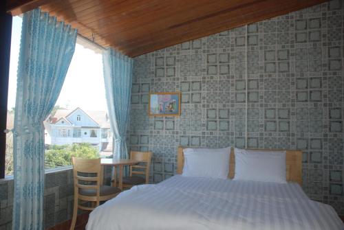 um quarto com uma cama, uma janela e uma mesa em Nhà M&G em Da Lat