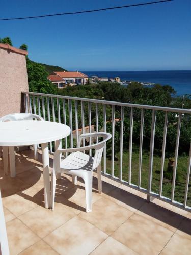 a balcony with a table and chairs and the ocean at Chambre d hôtes chez raymonde et sandrine in Luri