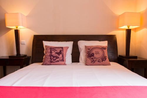 a bed with pink and white sheets and two lamps at Les Bastides du Golf d'Albret in Barbaste