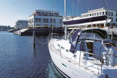 a white boat docked in the water in front of a building at Yachthafenresidenz Hohe Düne in Warnemünde