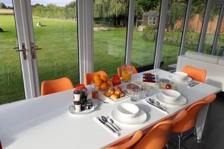 FIELDVIEW FARMHOUSE BED AND BREAKFAST في Colkirk: طاولة بيضاء عليها طعام وكراسي برتقالية