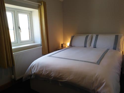 a bedroom with a large white bed with a window at FIELDVIEW FARMHOUSE BED AND BREAKFAST in Colkirk