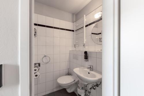 a white bathroom with a toilet and a sink at a&o Hamburg City in Hamburg