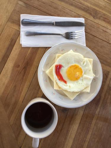 a plate with an egg on a table with a cup of coffee at XOXO Kuta Legian Hostel in Legian