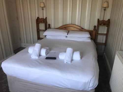 a white bed with white towels and a remote on it at Penny Farthing Hotel & Cottages in Lyndhurst