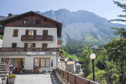 a building on a hill with mountains in the background at Albergo - B&B Alpina in Valdidentro
