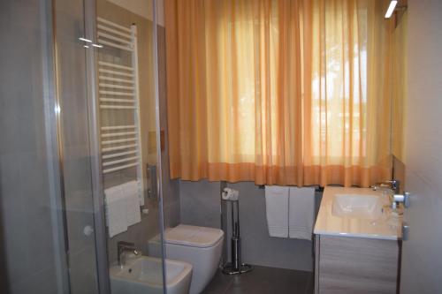 e bagno con servizi igienici, lavandino e doccia. di Orchidea Marina a Tirrenia