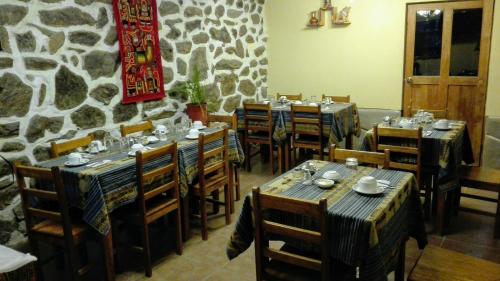 a restaurant with tables and chairs and a stone wall at B&B Chayana Wasi in Ollantaytambo