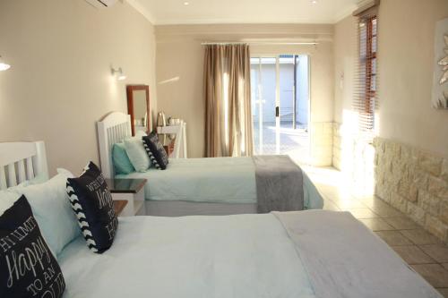 a bedroom with two beds and a hallway with a window at Lighthouse in Kroonstad