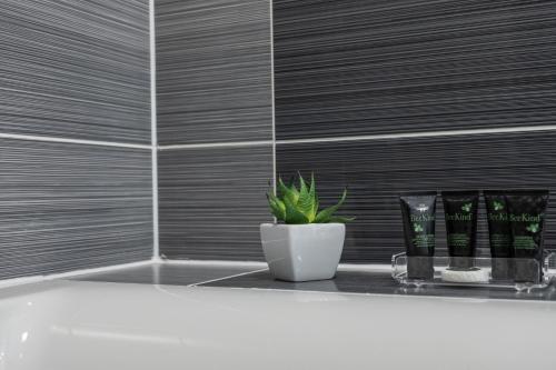 a bathroom with a white tub and a plant on a shelf at Burleigh Court Hotel and Leisure in Loughborough