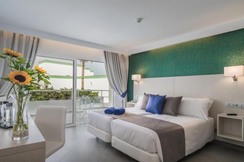ein Schlafzimmer mit einem großen Bett und einer Vase aus Blumen in der Unterkunft Aparthotel Esquinzo Y Monte Del Mar in Playa Jandia