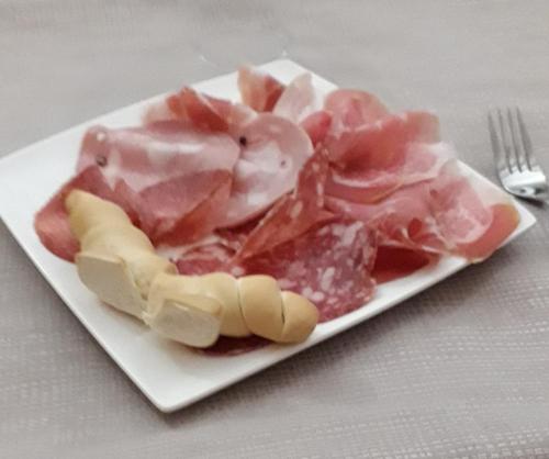 a plate of meat on a table with a fork at Da Santo Hotel Ristorante Pizzeria in Ferrara