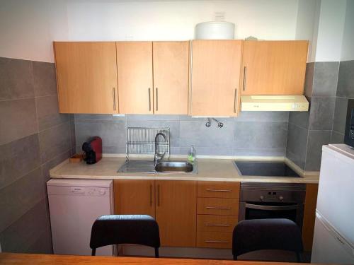 a small kitchen with wooden cabinets and a sink at Columbia Praia Da Rocha Apartamento in Portimão