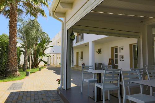 a patio with tables and chairs and palm trees at Donnosanto Residence in Torre Santa Sabina