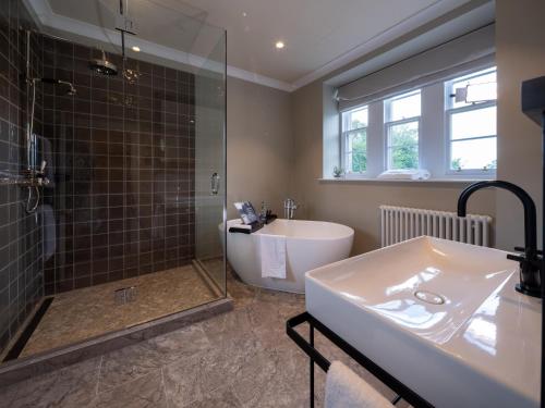 a bathroom with a tub and a sink and a shower at SCHLOSS Roxburghe, part of Destination by Hyatt in Kelso