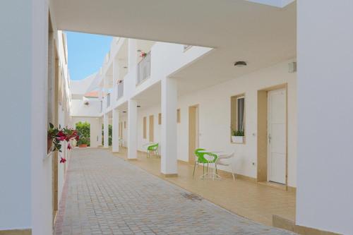 a hallway of a white building with chairs and tables at Donnosanto Residence in Torre Santa Sabina
