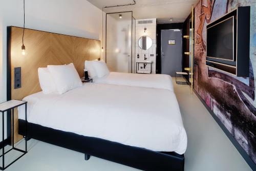 a bedroom with a large white bed and a flat screen tv at Hotel the Match in Eindhoven