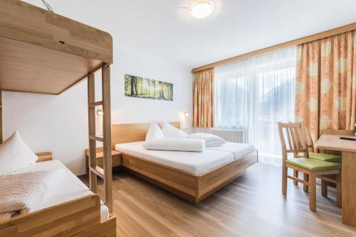 sypialnia z 2 łóżkami piętrowymi i biurkiem w obiekcie Gasthof Venedigerblick w mieście Neukirchen am Großvenediger