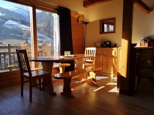 una sala da pranzo con tavolo, sedie e una grande finestra di Appartement lumineux avec balcon à Arêches Beaufort a Beaufort