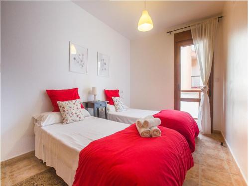 a bedroom with two beds with red sheets and a teddy bear at La Casa Del Polo- Alltarifa in Tarifa