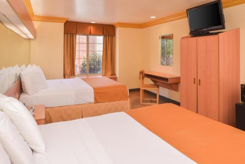 um quarto de hotel com duas camas e uma secretária em H3 Inn & Suites - LAX Airport - Los Angeles em Inglewood