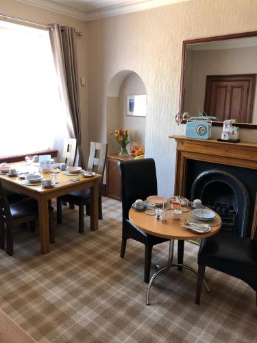 a dining room with two tables and a fireplace at Drumdale Bed and Breakfast in Inverness