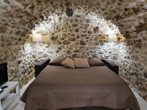 a bedroom with a bed and a stone wall at Il Grottino in Pescasseroli