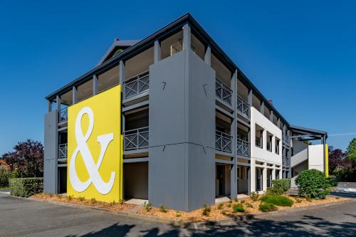an office building with a yellow and white sign on it at B&B HOTEL Périgueux Boulazac in Boulazac