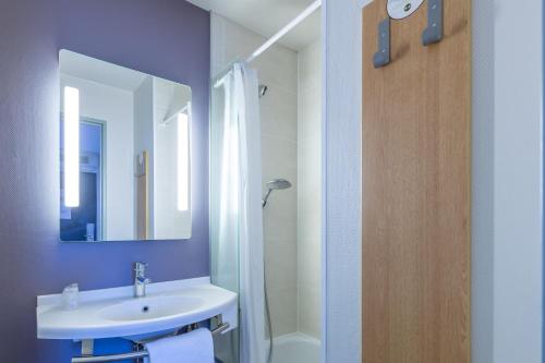 a bathroom with a sink and a mirror and a shower at B&B HOTEL Périgueux Boulazac in Boulazac