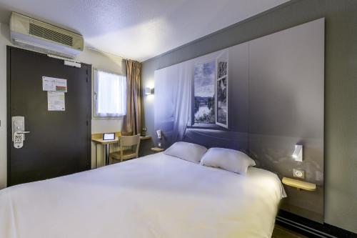 a hotel room with a large bed with two pillows at B&B HOTEL Périgueux Boulazac in Boulazac