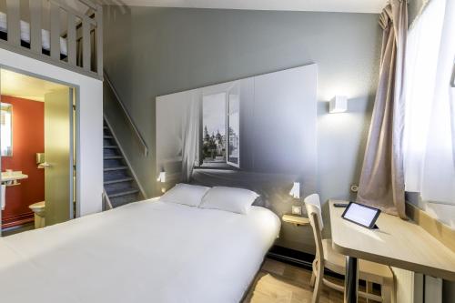 a bedroom with a bed and a desk with a laptop at B&B HOTEL Périgueux Boulazac in Boulazac