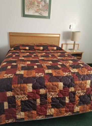 a bed with a quilt on it in a room at Oregon Trail Motel and Restaurant in Baker City
