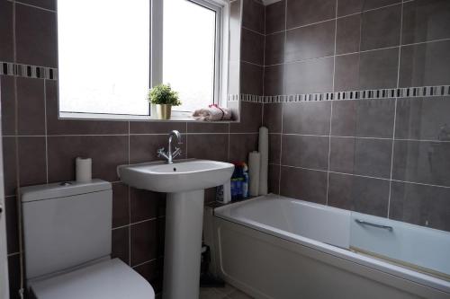 ein Badezimmer mit einem Waschbecken, einem WC und einer Badewanne in der Unterkunft Idyllic 3-bed House. 5-min from Channel Tunnel in Folkestone