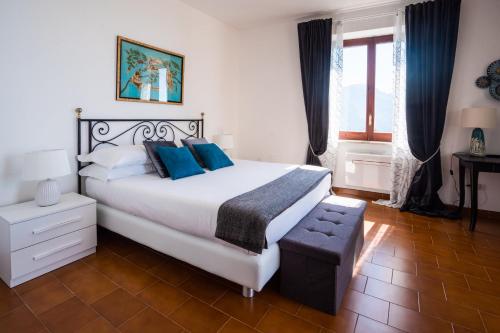 a bedroom with a large white bed with blue pillows at Sea View Villa in Ravello with lemon pergola, gardens and jacuzzi - Ideal for elopements in Ravello