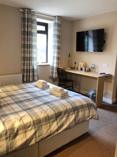 a hotel room with a bed and a desk and a kitchen at The Old Stables in Moffat