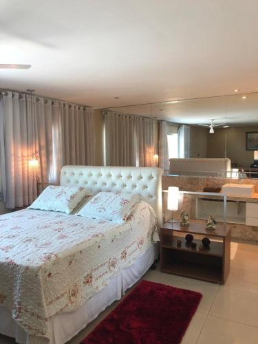 a bedroom with a large white bed and a mirror at Victor Plaza Formiga in Formiga