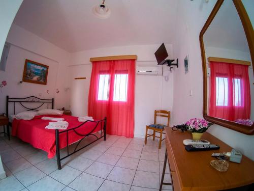 a bedroom with a bed with red curtains and a table at The Captain in Elafonisos