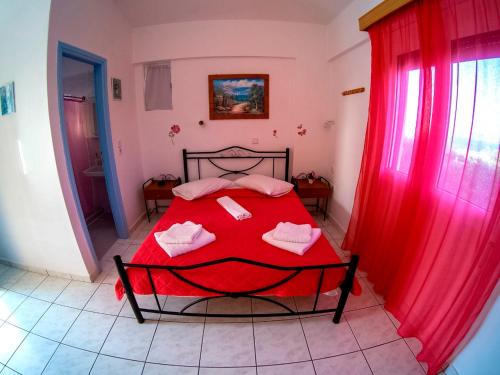 a bedroom with a red bed and red curtains at The Captain in Elafonisos