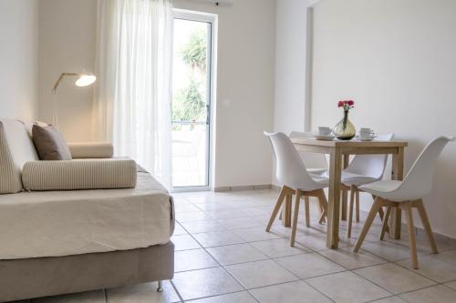 a living room with a table and white chairs at Pinelopi Hotel in Platanes