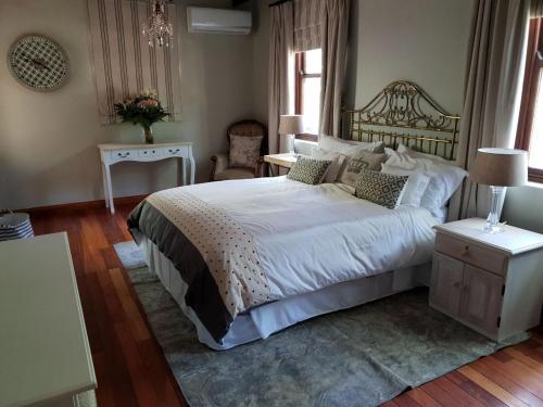 a bedroom with a large white bed and a table at Angel Oak guesthouse in Brits
