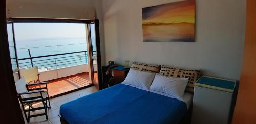 sypialnia z niebieskim łóżkiem i balkonem w obiekcie Joanna's Seaside Villa w mieście Kallithea