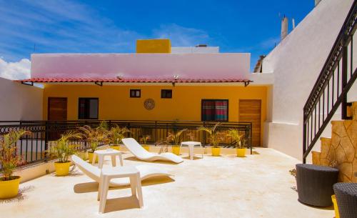 eine Terrasse mit weißen Stühlen und ein gelbes Haus in der Unterkunft AKBAL Playa - Beach Zone in Playa del Carmen