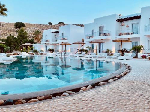 a large swimming pool in front of a hotel at Caesars Gardens Hotel & Spa - Adults Only in Lindos