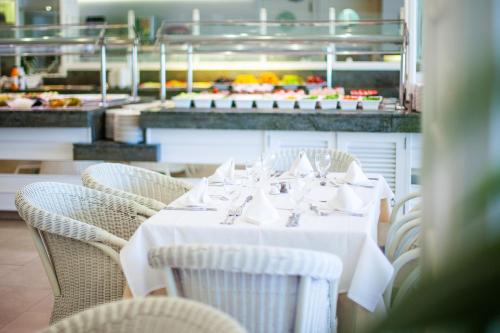 a table with white tables and chairs in a restaurant at Grupotel Club Menorca in Son Xoriguer