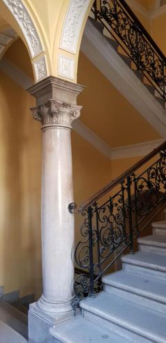 a staircase with a white column and wrought iron railing at Boudoir Budapest Apartment in Budapest