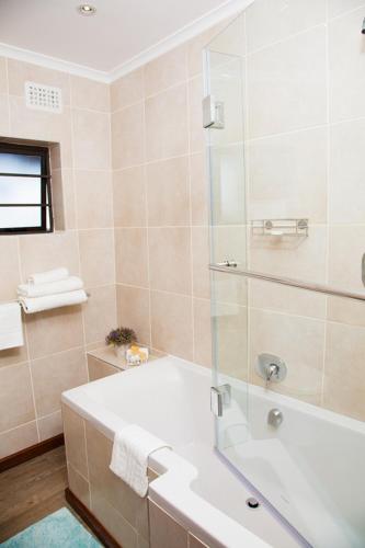a bathroom with a tub and a glass shower at WarmKaros Bed & Breakfast in East London