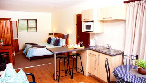 Una habitación con cocina y un dormitorio con cama. en WarmKaros Bed & Breakfast, en East London