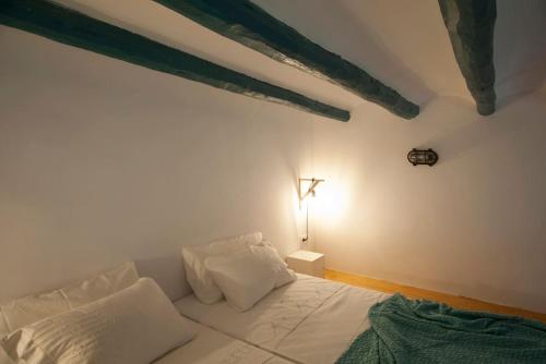 - une chambre dotée d'un lit blanc avec une croix sur le mur dans l'établissement Portolà, 1 apartament, à Balaguer